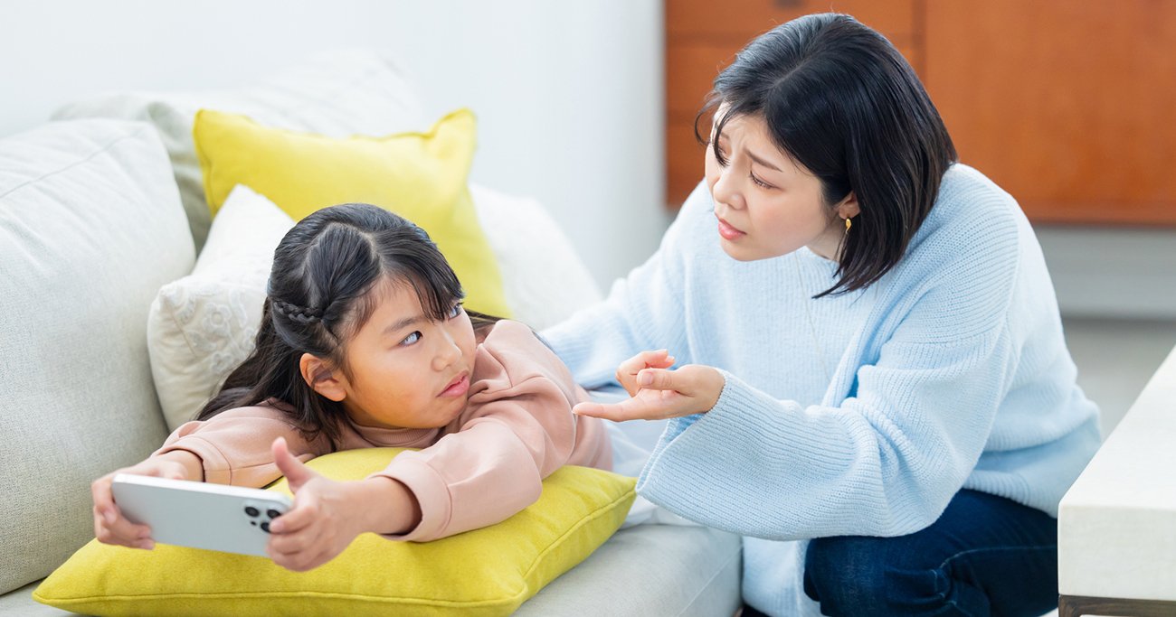 ゲームをする子どもに話しかける母親