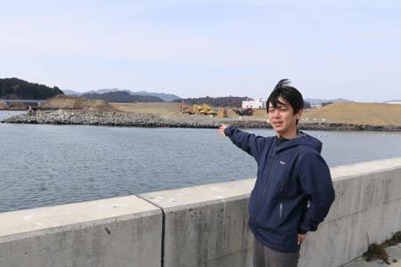 設計ミスを見つけた浜辺を指す鈴木卓也さん