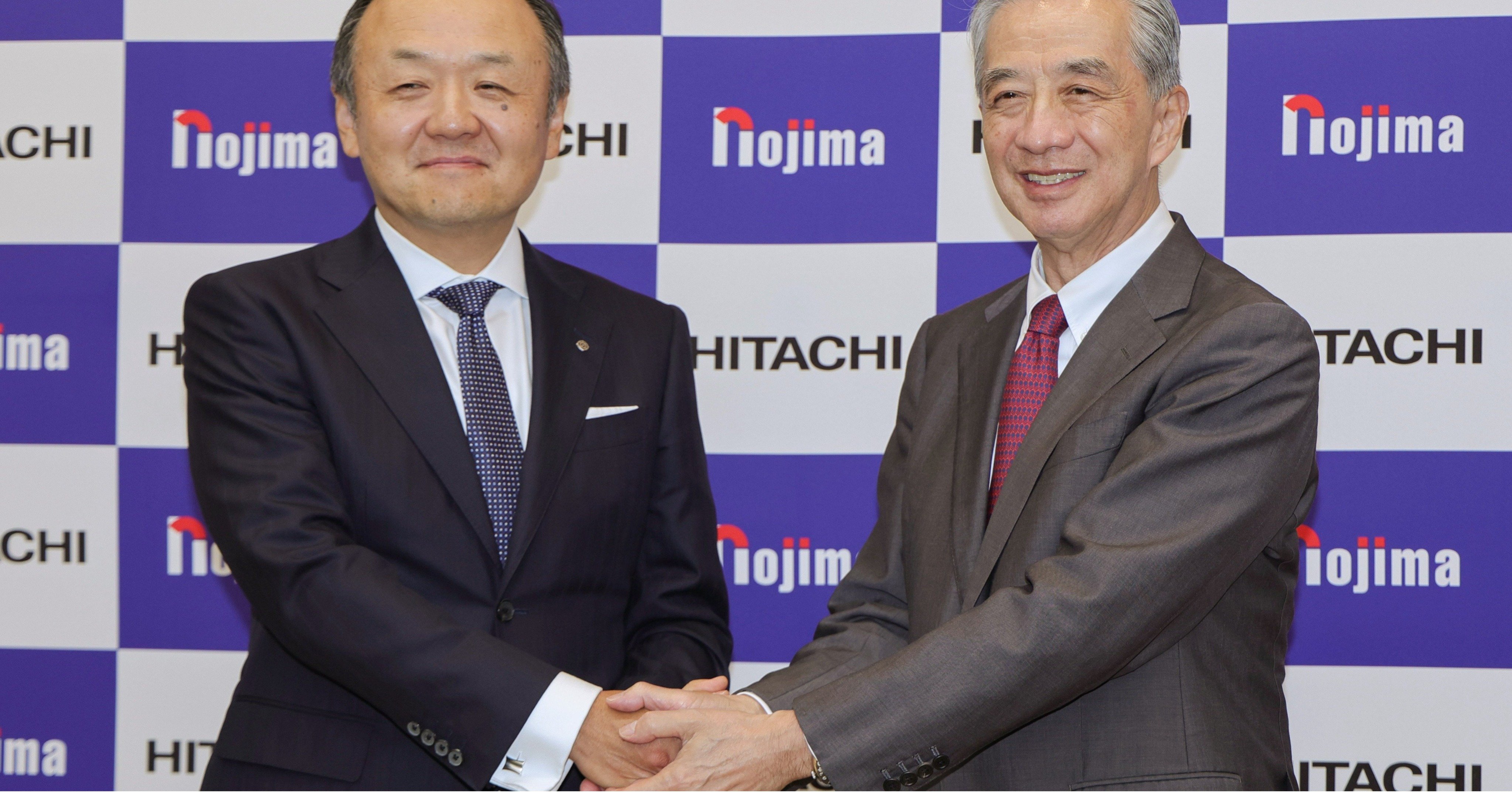 記者会見で握手するノジマの野島広司社長（右）と日立製作所の網谷憲晴執行役専務（左）