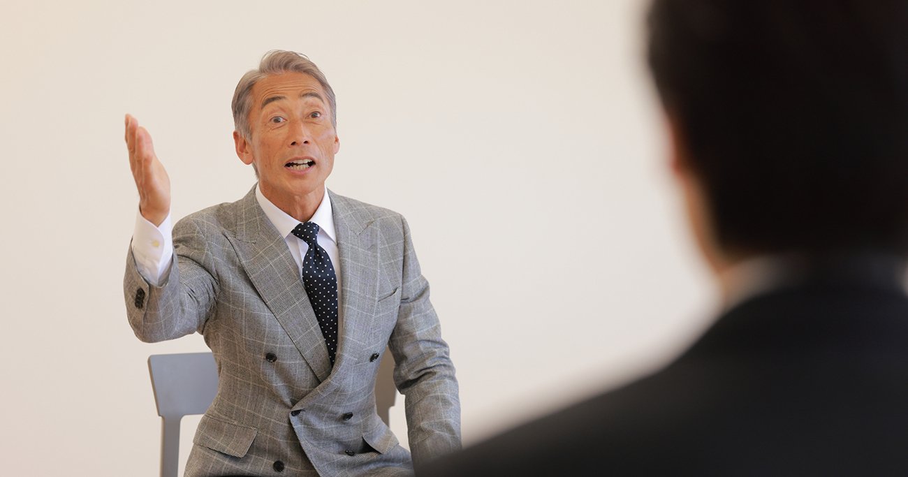 面接で身ぶりを交えて話す中高年の男性