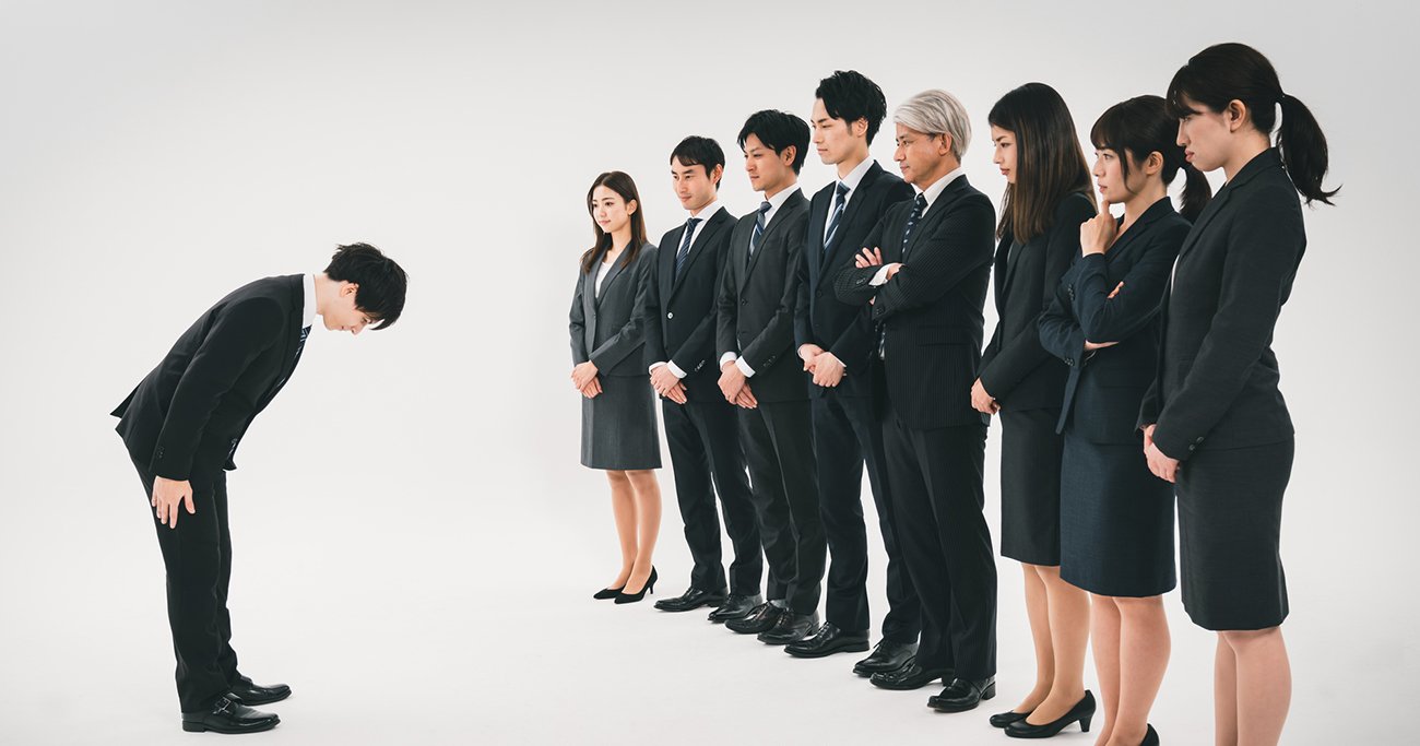 頭を下げる男性と職場のメンバー