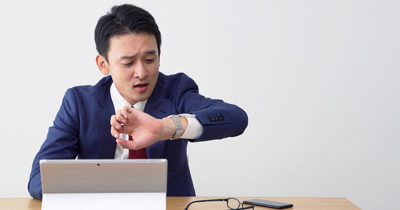デスクで腕時計を見るビジネスマン