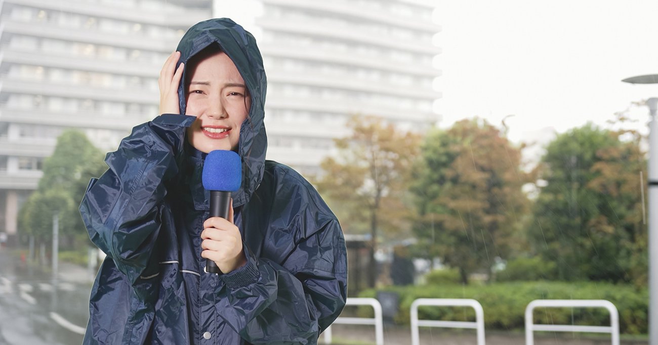 雨の中で中継する女性リポーター