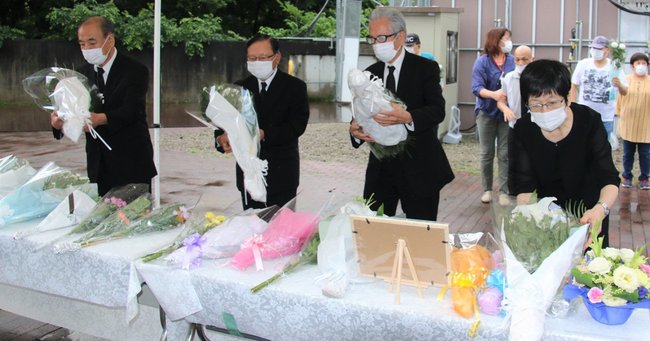障害者施設「津久井やまゆり園」前に設置された献花台で、花を供える参列者（7月26日撮影）　