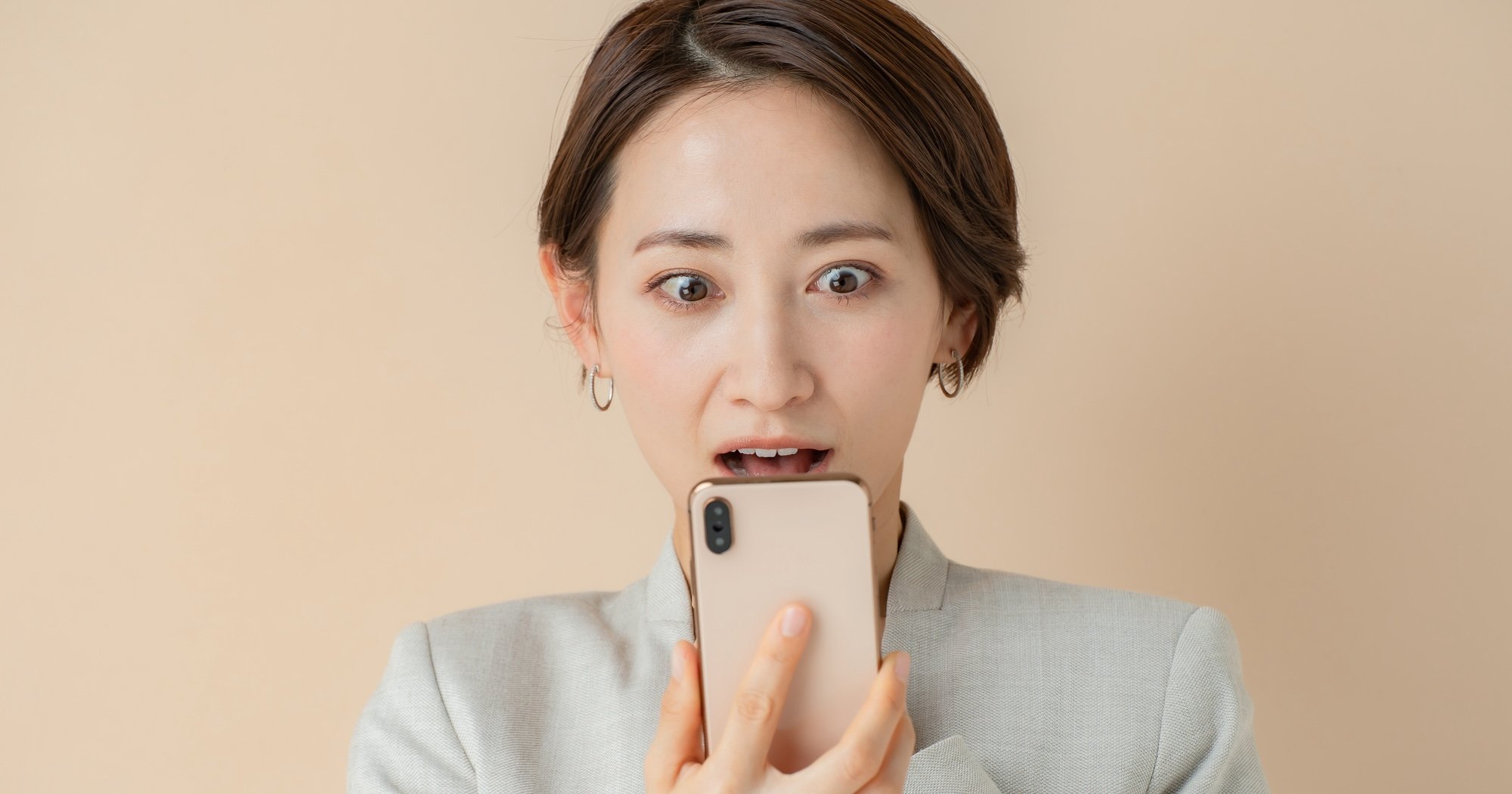 スマホの画面を見て驚く女性