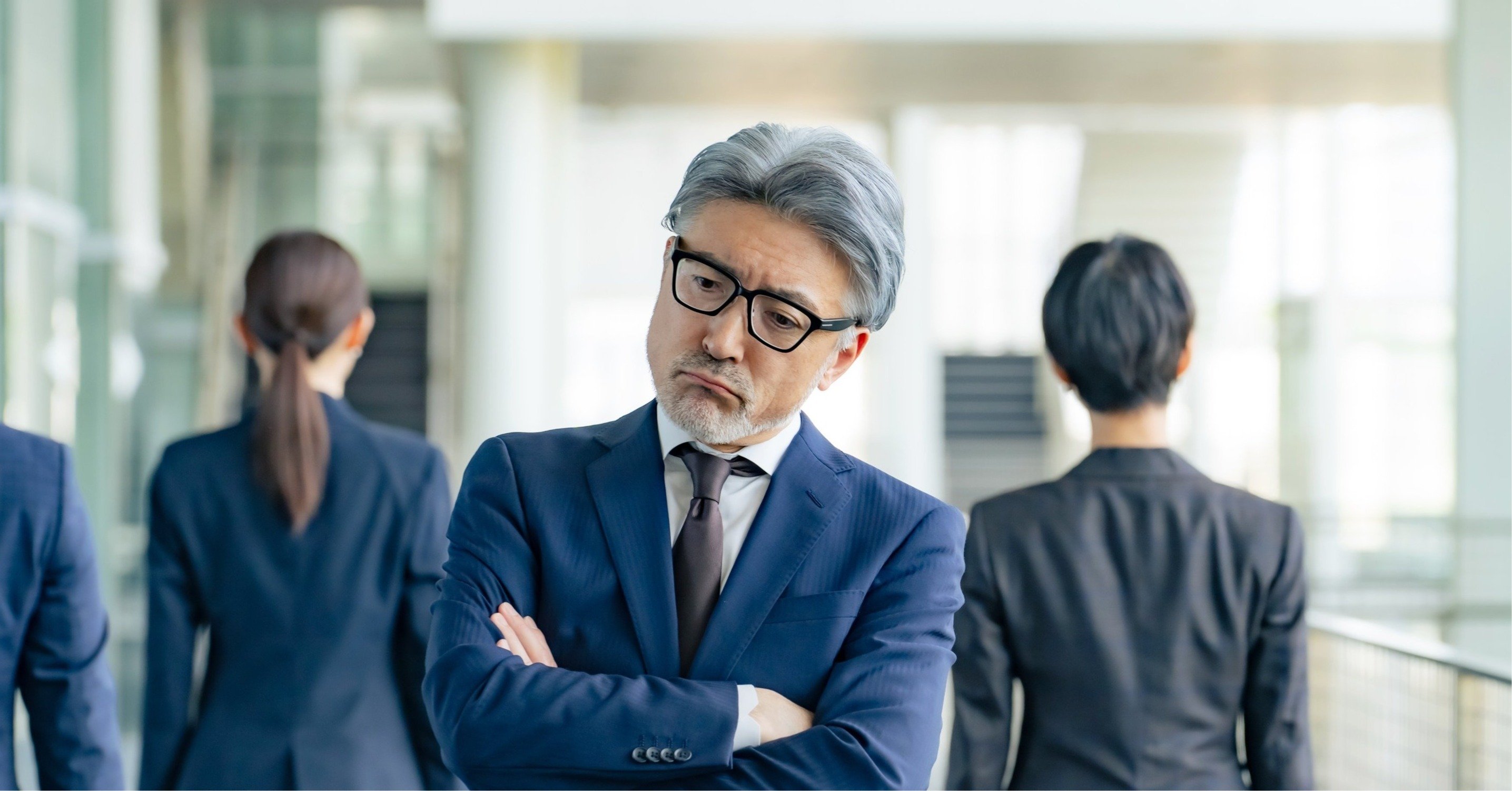 部下に背を向けて悩むシニア男性ビジネスパーソン