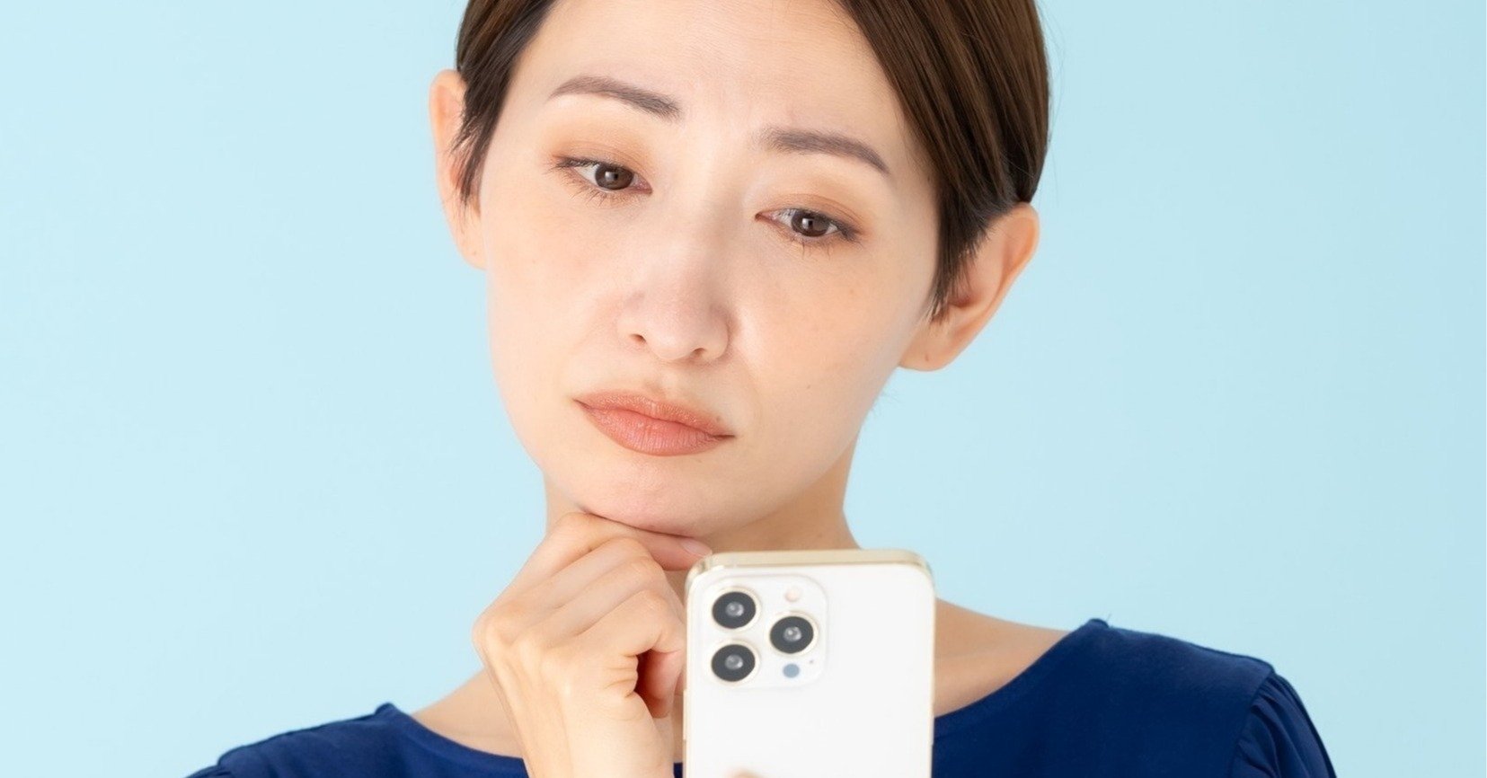 スマホを眺めて首を傾げる女性