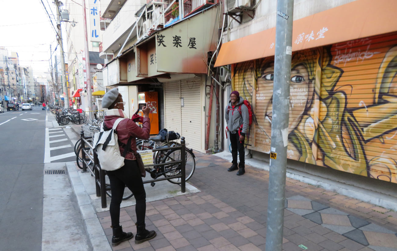 カレー店「薬味堂」のシャッター前で記念撮影する外国人観光客。今や、西成は、「日本のハーレム」として外国人観光客の間で認知が進みつつあるようだ