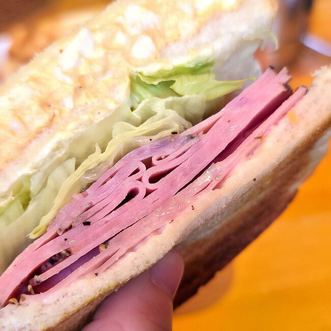 「おいしすぎて昨日も食べた」コメダ珈琲の“お肉たっぷりサンド”持つだけで具材があふれそうなんだけど…!「ハムの量がハンパない」「厚みやばかった」