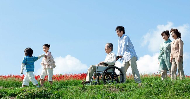 車椅子を押されて家族と散歩する高齢男性
