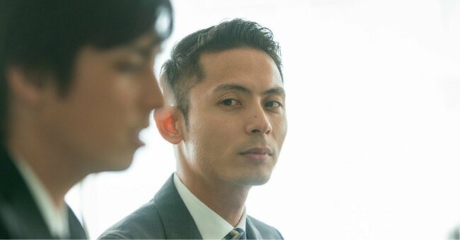 同僚を嫉妬の目で見る男性