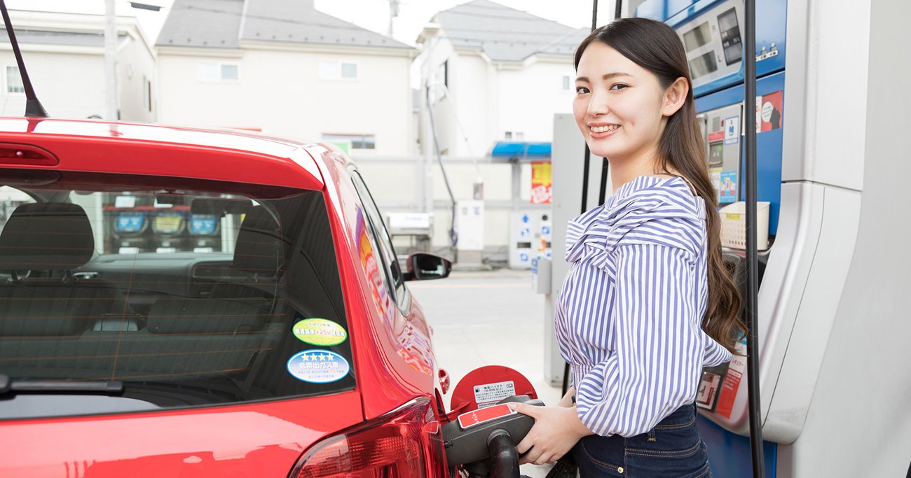 ガソリンスタンドで車に給油する女性