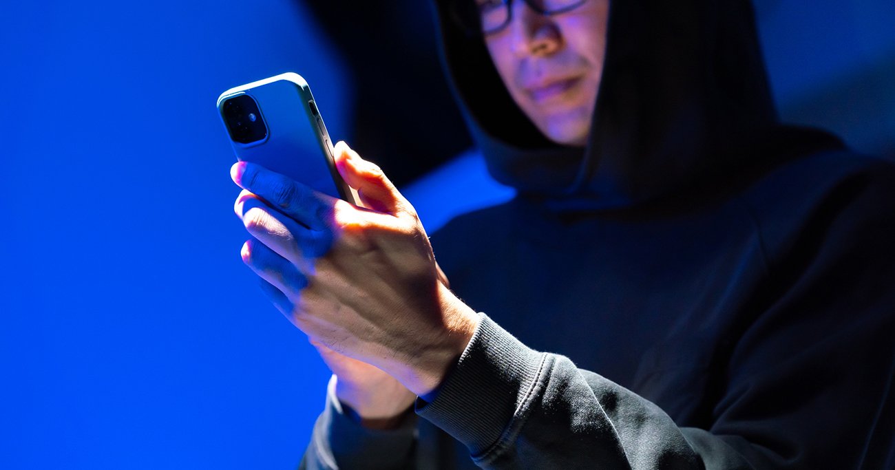 スマートフォンを操作するフード姿の人物
