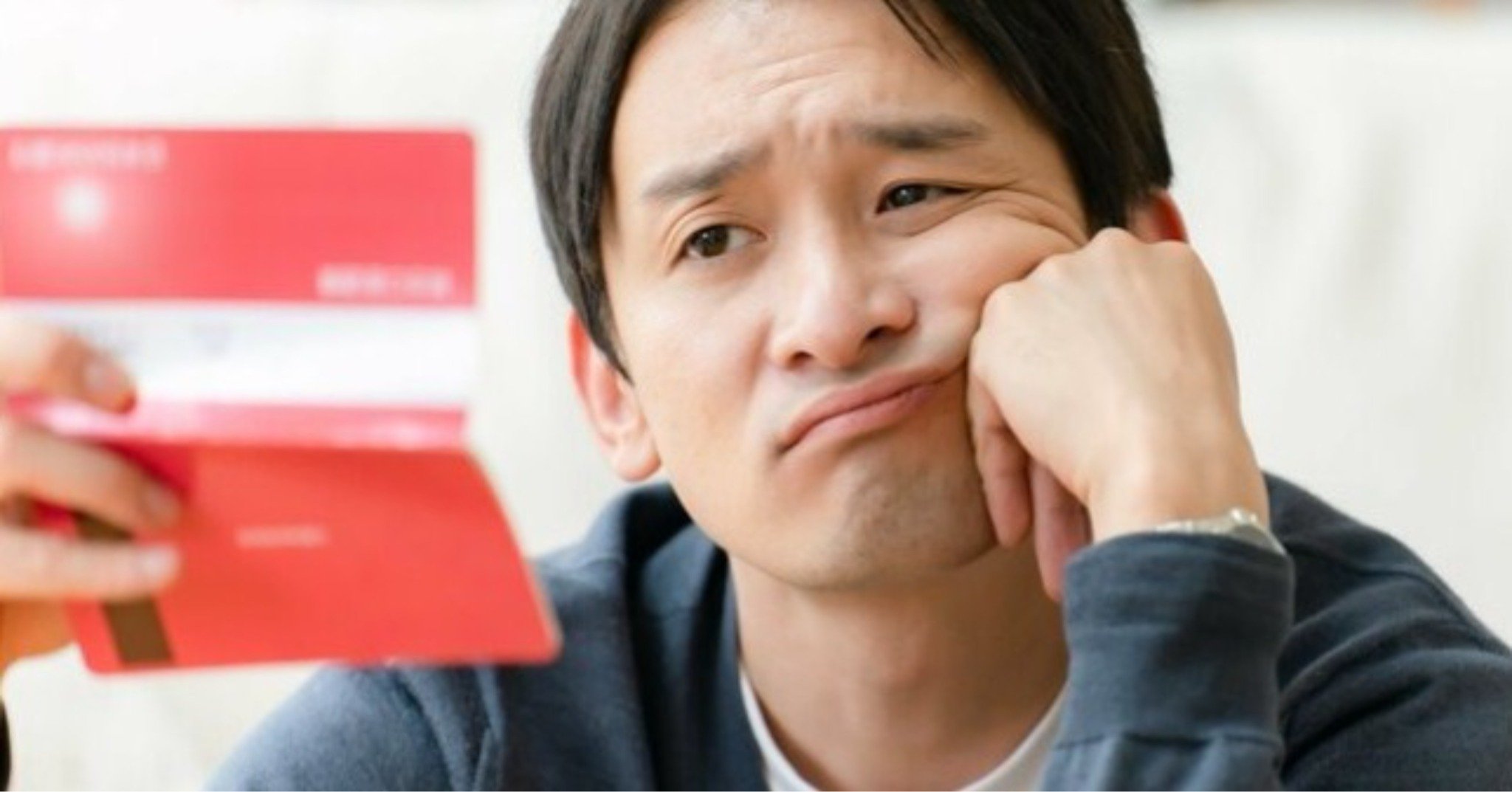 通帳を見て悲しい表情を浮かべる男性