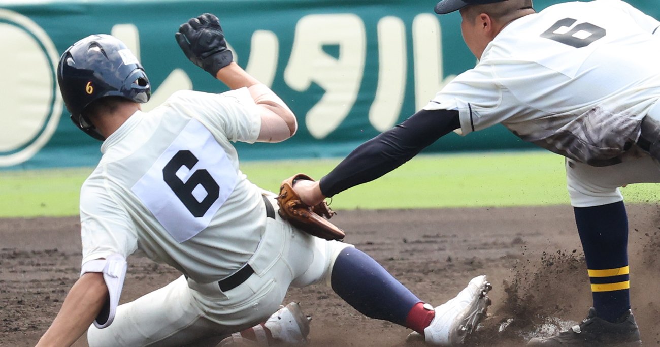 甲子園の試合でスライディングする走者とタッチを試みる野球選手