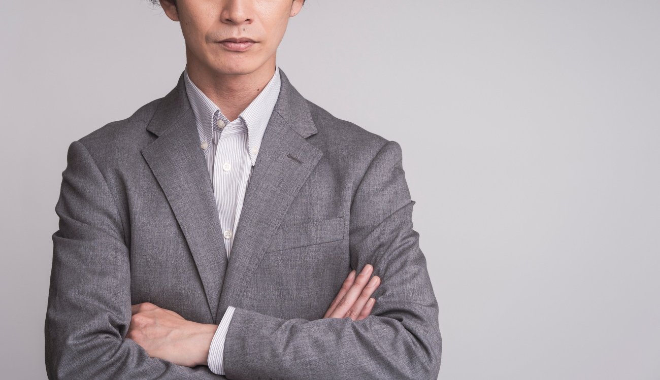 ジャケットを着ている男性が腕組みをしている。
