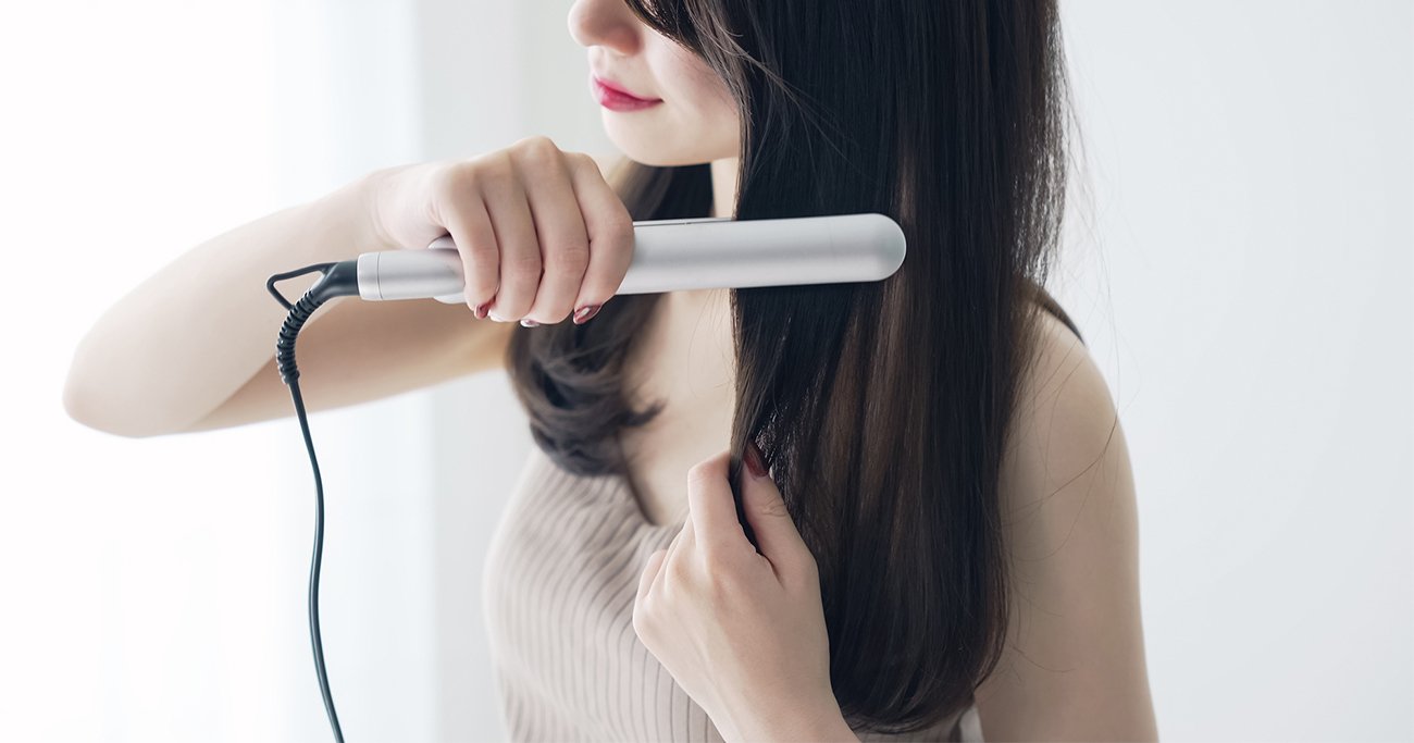 ヘアアイロンで髪を整える女性