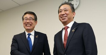 握手する永松文彦社長と阿久津知洋執行役員