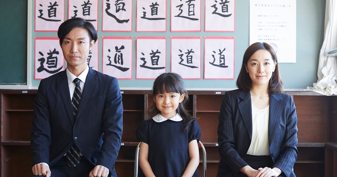 教室で並んで座る両親と子ども