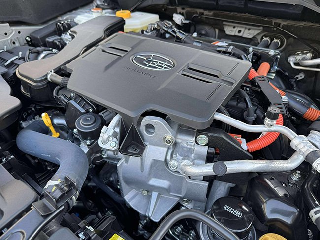水平対向ユニットの上に樹脂カバー、周囲には高電圧(オレンジ)ハーネスが走る。ハイブリッド化しつつも配索は整然としている