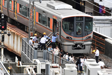 大阪北部地震で係員に誘導されて電車から避難する人々