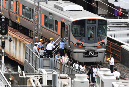 大阪北部地震で係員に誘導されて電車から避難する人々