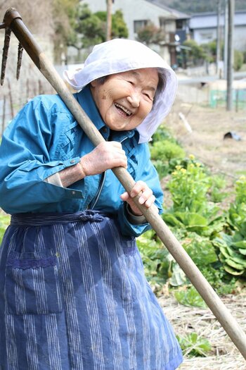 写真：農具をかついでゴキゲンに笑う石井哲代さん102歳