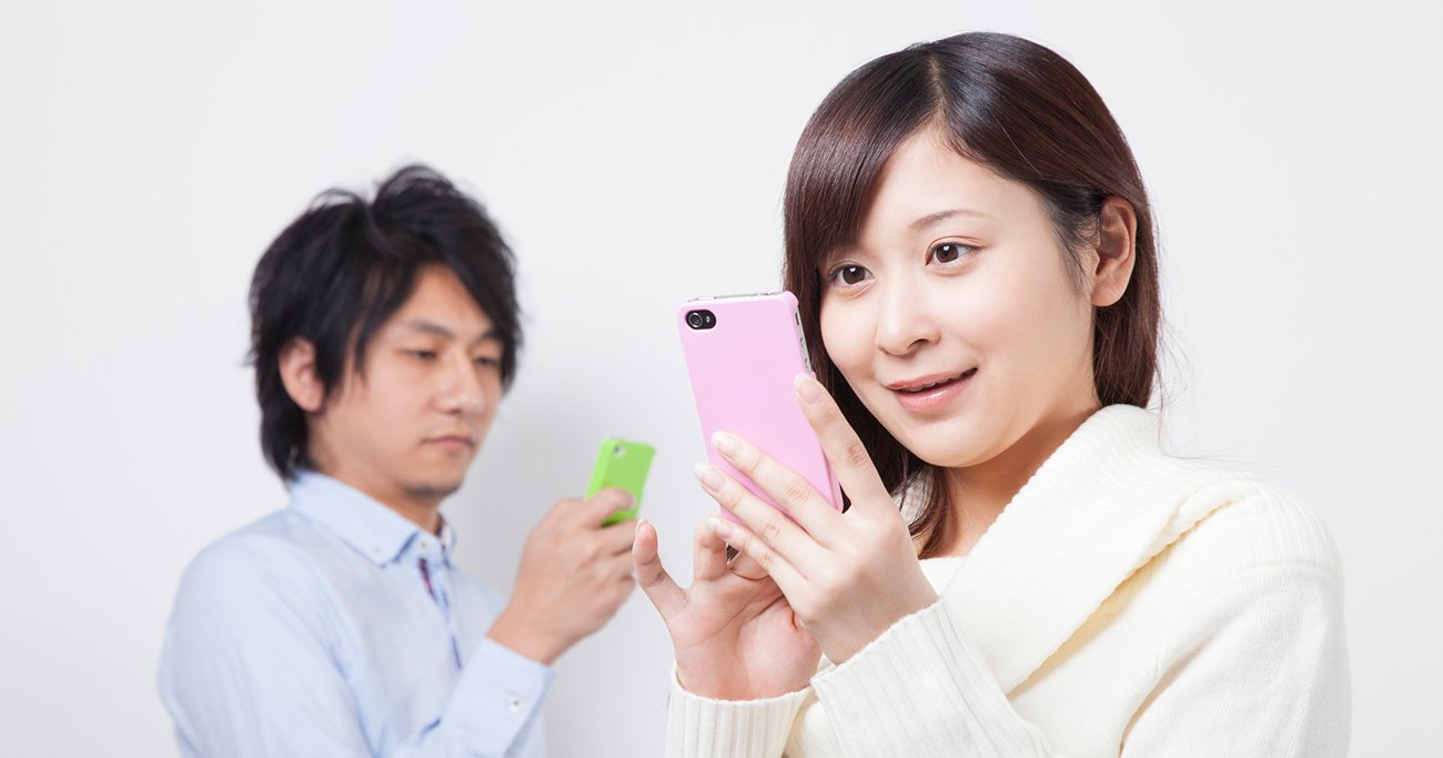 スマートフォンを見ながらやり取りする男女