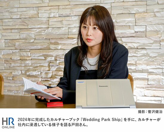 2024年に完成したカルチャーブック『Wedding Park Ship』を手に、カルチャーが社内に浸透している様子を語る戸田さん。