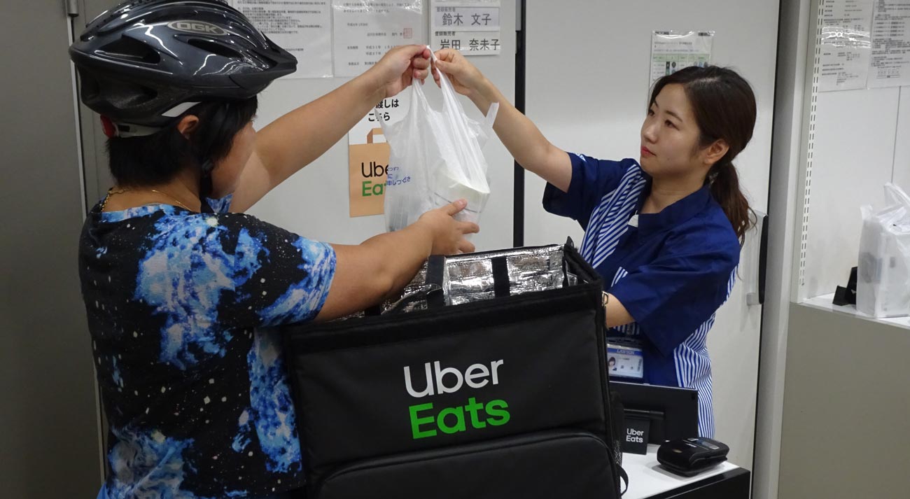 ローソンの商品を運ぶウーバーイーツの配達員。利便性は高まるが、配達員の労働問題も指摘されている