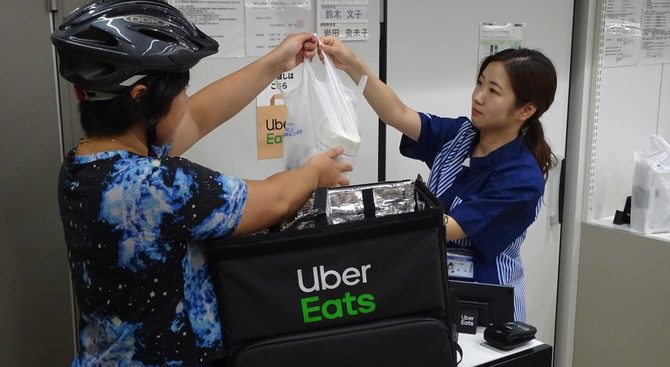 ローソンの商品を運ぶウーバーイーツの配達員。利便性は高まるが、配達員の労働問題も指摘されている