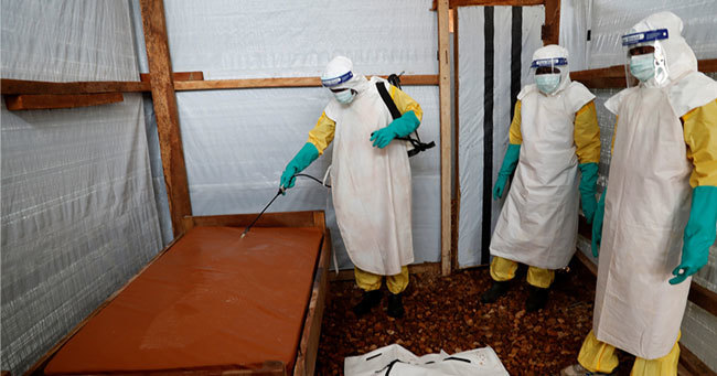 エボラでの死亡が疑われる乳幼児のベッドを消毒する医療従事者
