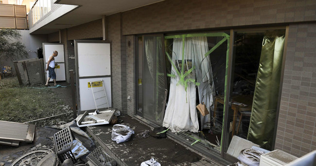 台風19号が通過した東京で壊れた住宅を掃除する男性