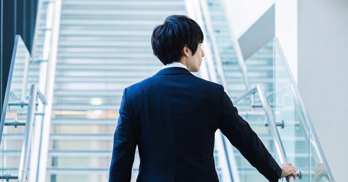 階段を上るスーツ姿の男性の後ろ姿