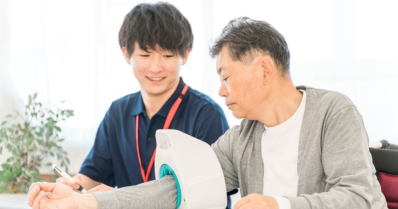 医療スタッフに血圧を測ってもらう男性