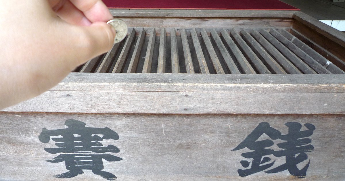賽銭箱に小銭を入れる手