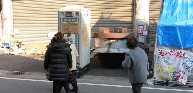 路上で寝ている人を物珍しそうに見る観光客たち