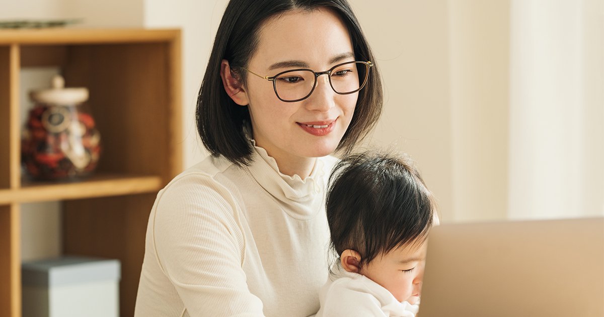 赤ちゃんを抱っこしながらパソコンを使う主婦