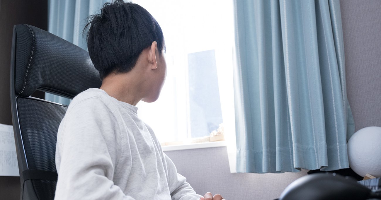 部屋で窓の外を見つめる子ども