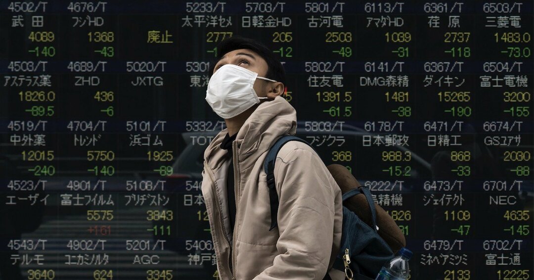 株価ボードとマスクをした男性