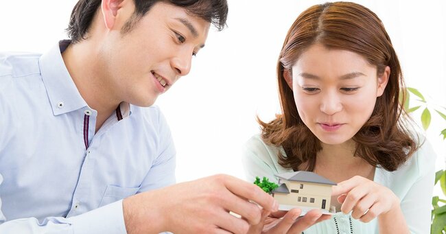 ミニチュアの家を手にする夫婦