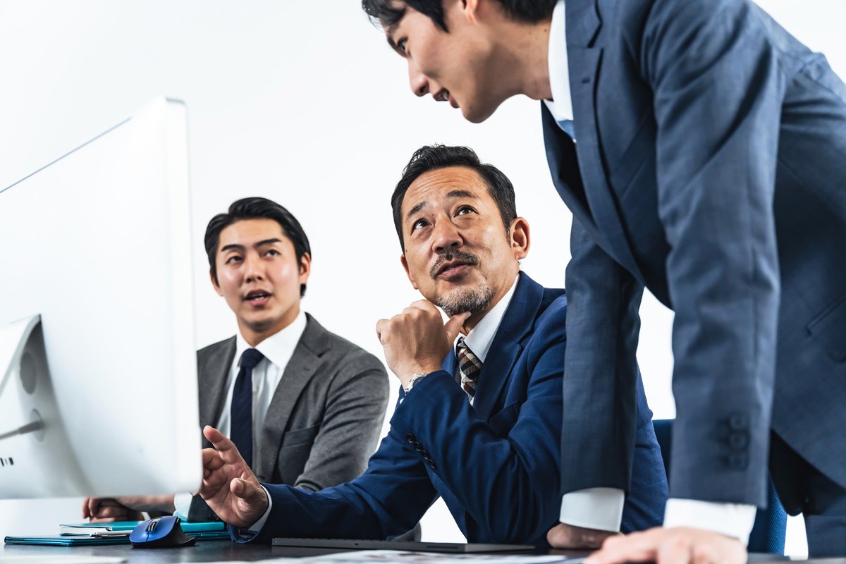 写真：パソコン画面を見ながら会議するビジネスマン