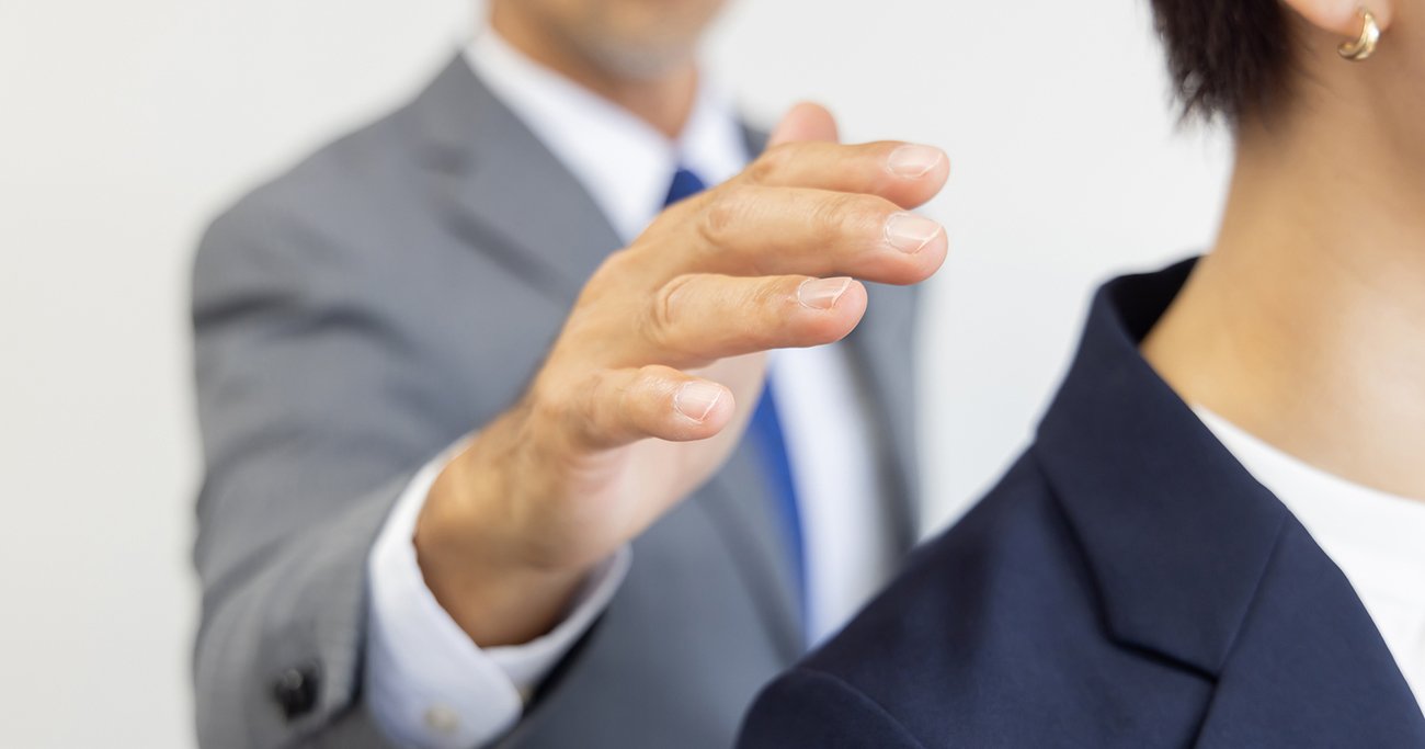 女性の肩に触れようとする男性