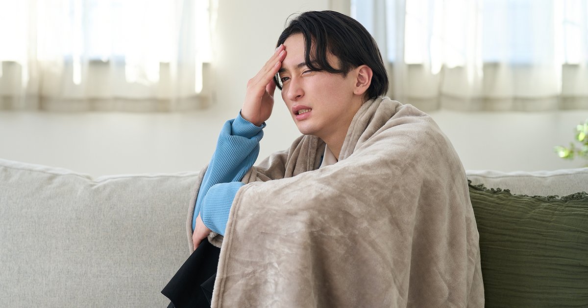 寒気がして毛布にくるまる男性