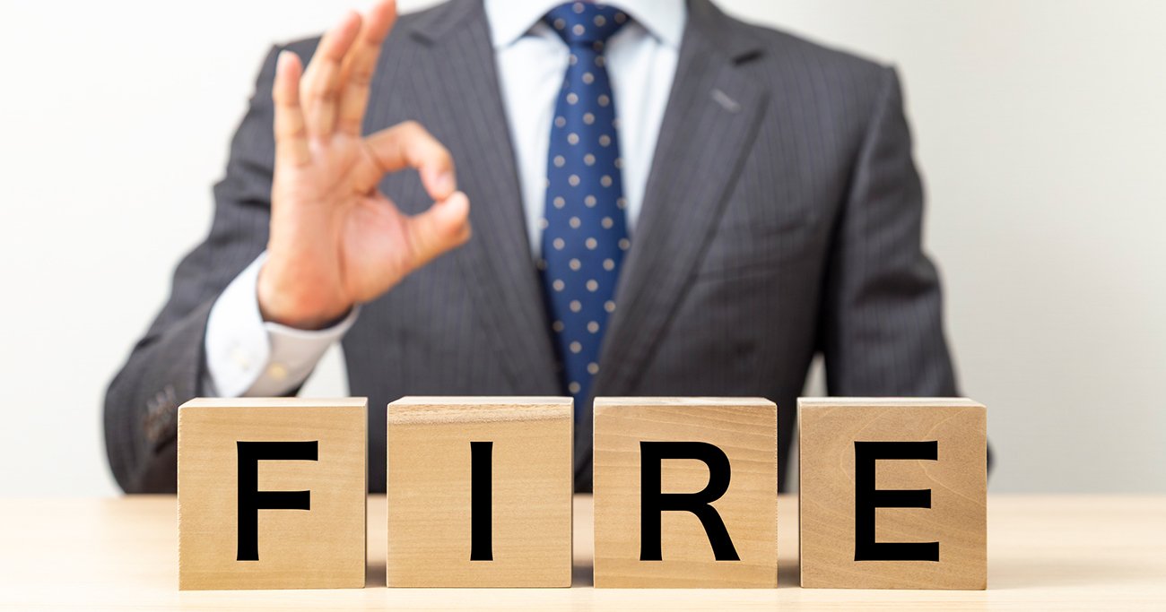 「FIRE」の文字が並ぶブロックとOKサインをする男性