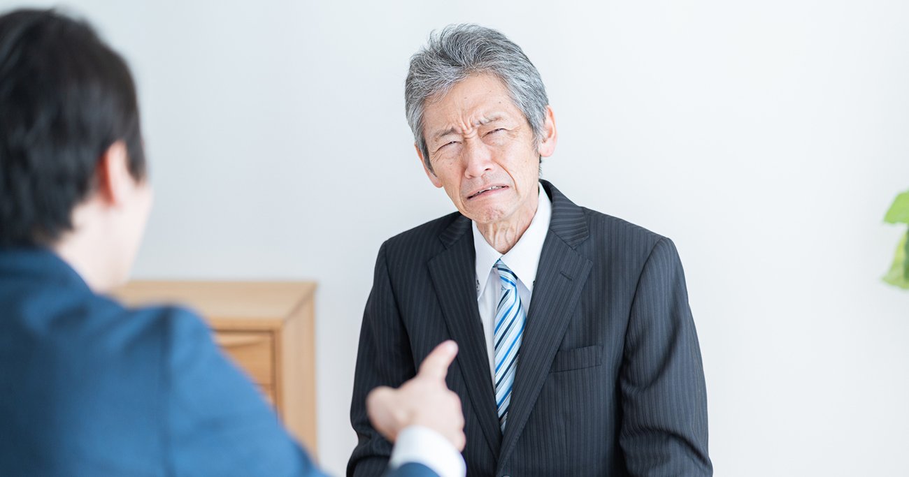 困った表情を見せる高齢男性と話す男性