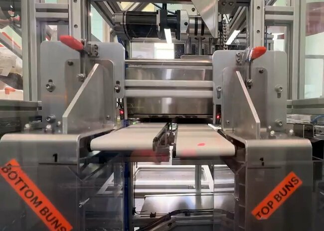 ニューヨークにあるカーネルの店舗でバンズの表面を焼く工程のため、機械がバンズをベルトコンベヤーに乗せる