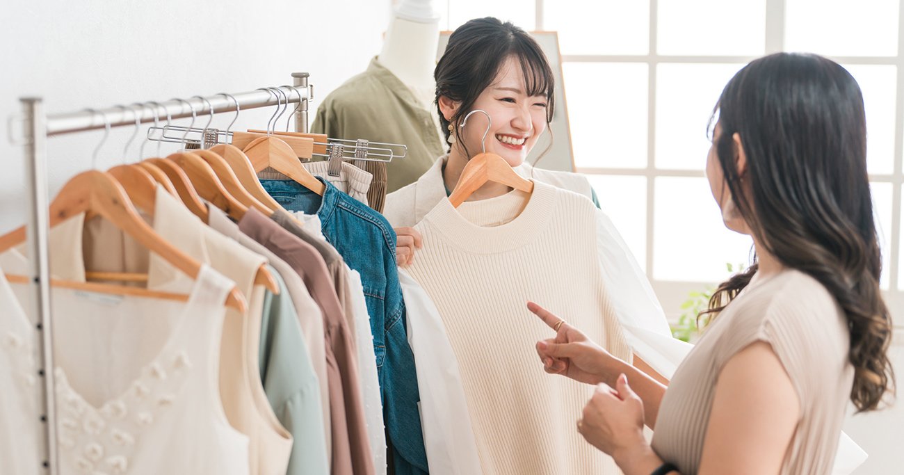 洋服を手に接客する女性店員と客の女性