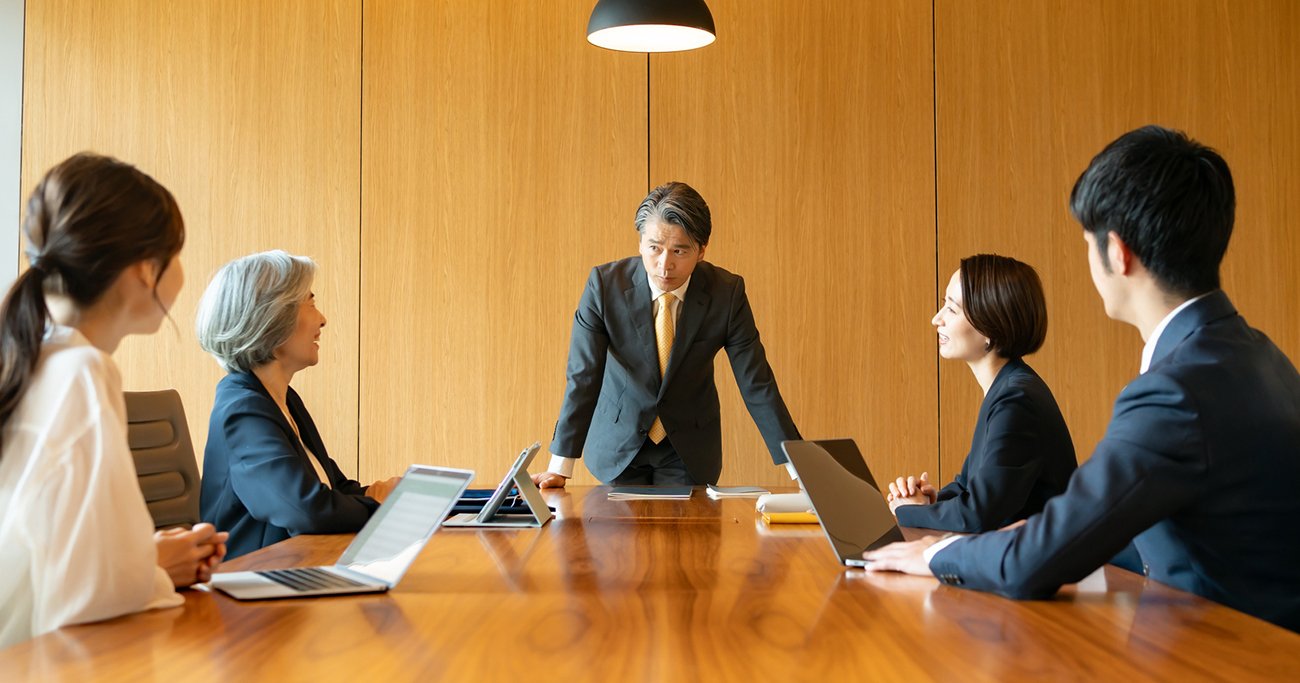 会議で社員たちに話をする中高年の男性
