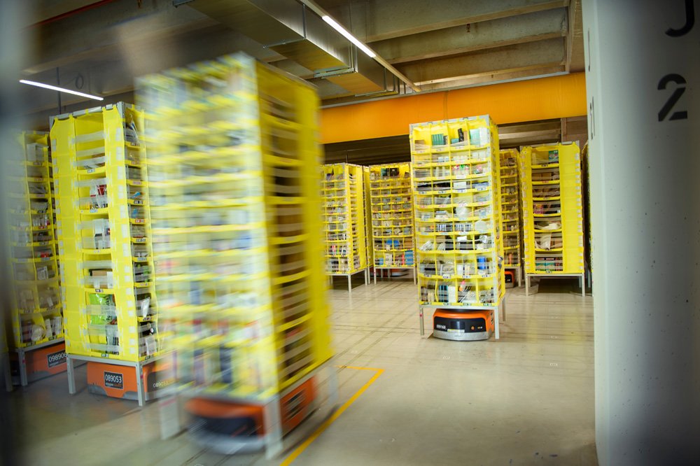 輸送ロボットがアマゾン物流センターの製品倉庫で輸送可能な棚を移動させている
